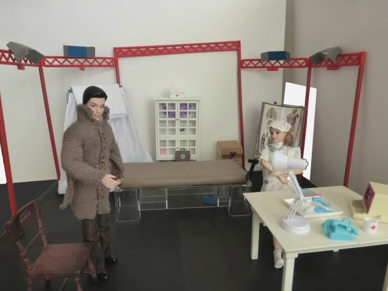 Doll dressed as a patient with nurse doll at desk